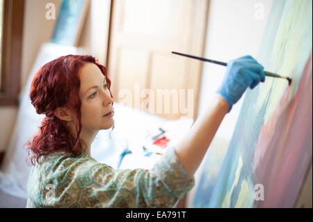 Portrait of middle-aged woman painting on canvas Stock Photo