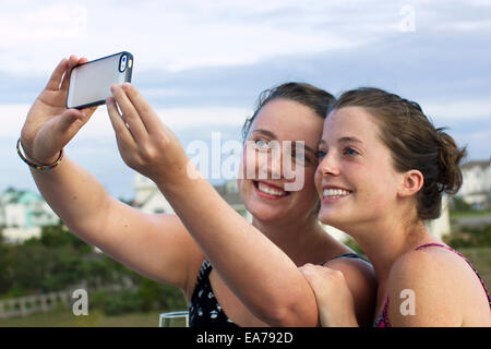Portrait of two young women photographing themselves and smiling Stock Photo