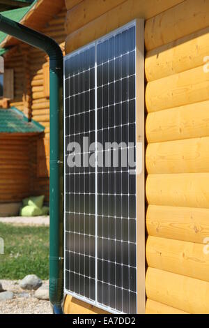 Solar battery on the yellow wall of a wooden house Stock Photo