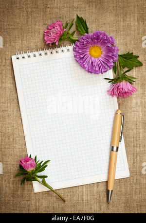 Notebook with pen and asters on canvas background Stock Photo