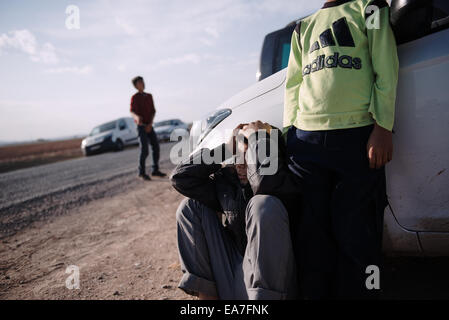 Kurdish children wait outside a cemetery, during the funeral of YPG fighters at the Turkish town of Suruc, near the Turkish-Syrian border. The YPG Fighters died while fighting Islamic State forces at the siege of the Syrian town of Kobani. Thousands of Kurdish people were forced to abandon the Syrian town of Kobani, which is under siege by Islamic State forces. Most of them are living in refugee camps in the Turkish town of Suruc. Stock Photo