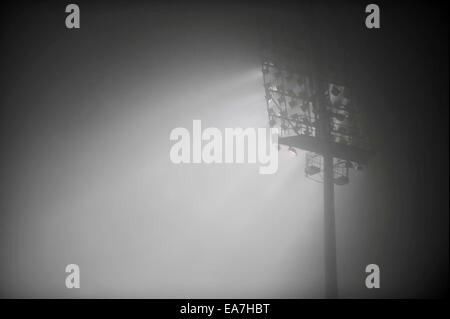 Football stadium floodlights are seen through dense fog in the night Stock Photo