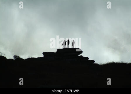 Three Silhouetted figures standing together on top of Trencrom Hill near St Ives Penwith West Cornwall South West England UK Stock Photo