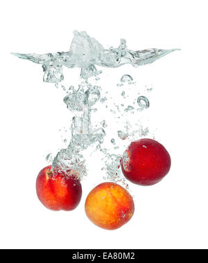 Isolated shot of peach falling into water, isolated on white background Stock Photo