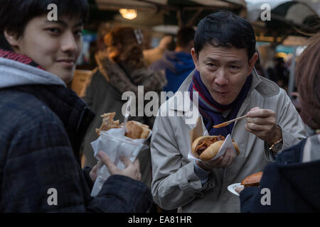 People eating sandwiches at the Real Food Market. Held weekly, Friday-Sunday, on Southbank Centre Square, it hosts over 40 small producers and independent traders of  fresh, high quality, great value food and drink. Stock Photo