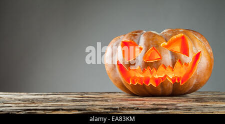 Scary halloween pumpkin on wooden planks with grey background with space for text. Stock Photo