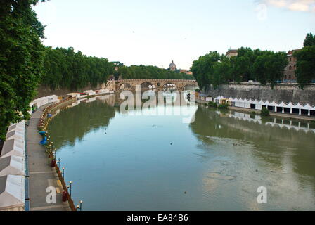 Tiber river running through Rome surrounded by festival tents and an arched bridge. Stock Photo
