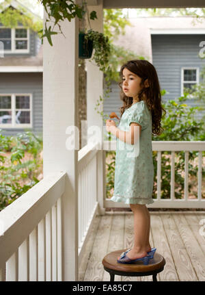 young girl in play shoes standing on stool on porch Stock Photo