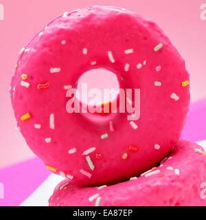 closeup of some appetizing donuts coated with a pink frosting and sprinkles of different colors Stock Photo