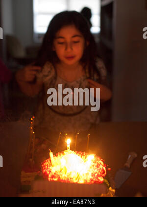 Young girl at home blowing out candles on a Birthday Cake. Stock Photo