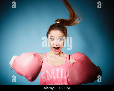 Funny girl female boxer in big fun pink gloves playing sports boxing hair motion studio shot blue background Stock Photo