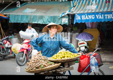 Vietnamese woman selling fresh fruit from bicycle at Dong Xuan Market in Hanoi's Old Quarter Stock Photo