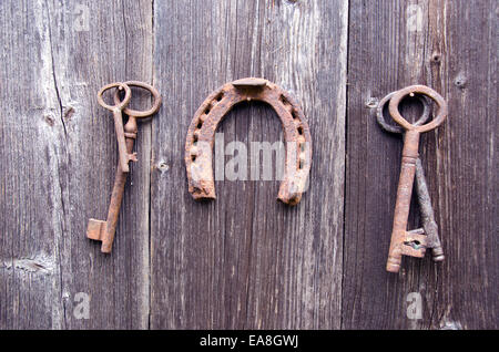 rusty ancient key and vintage horseshoe collection on old wooden barn wall Stock Photo