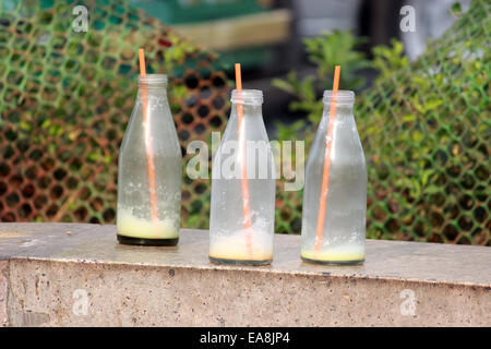 Bottles, straw, milk, three, glass,empty, putting on the wall in Connaught place, New Delhi, India. Stock Photo