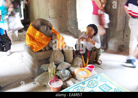 Cambodian people sitting for pray with Vishnu image statue Cambodian Style at Ta Prohm temple on April 13, 2009 in Siem Reap. Stock Photo