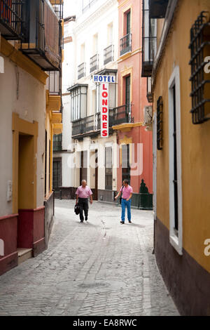 Two men walking down typical old cobbled street in near Hotel Londres, Seville, Spain Stock Photo