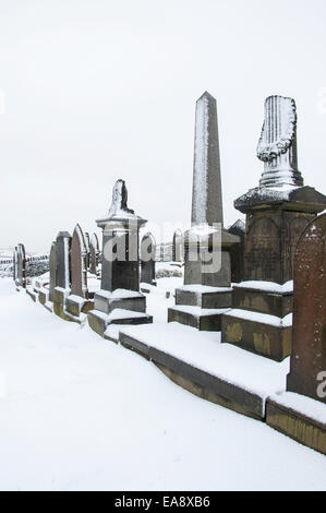 Snow covered gravestones and monuments in a hillside graveyard in Charlesworth near Glossop, Derbyshire. Stock Photo