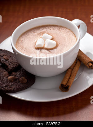 A fresh creamy cup of home made hot chocolate with marshmallows, chocolate chip cookies, and cinnamon. Stock Photo