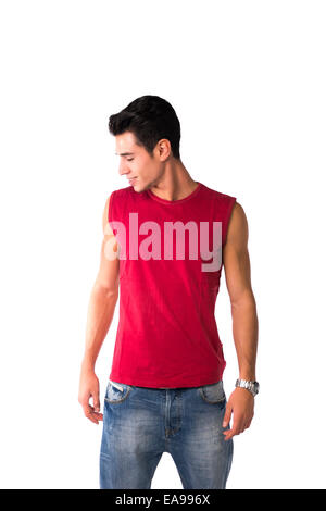 Attractive smiling young man in red sleeveless shirt and jeans, looking down at blank space next to him, isolated on white Stock Photo