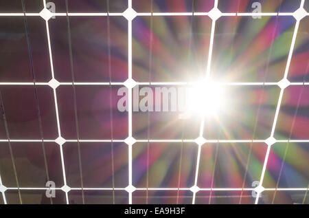 Solar panels wit sun burst flare. Solar panel seen from behind, underneath. Solar cells on clear glass with sun shining through. Stock Photo