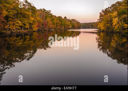 Colorful Autumn foliage reflects on the glassy surface of a still lake at dusk in Atlanta's Stone Mountain Park. USA. Stock Photo