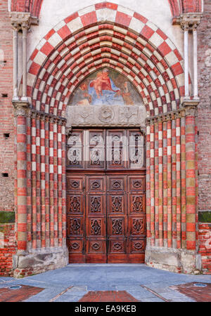 Old vintage wooden door at the entrance to catholic church in Alba, Italy (vertical composition). Stock Photo