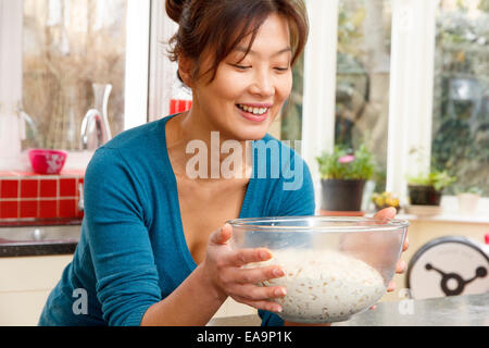 The dough for this white seeded loaf has been placed into a bowl and risen.  The Korean Asian female is very happy. Stock Photo