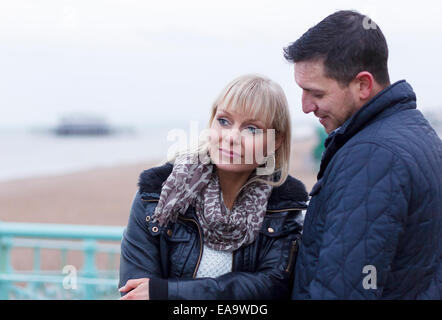 A thoughtful moment for a couple on a day out at the British seaside in Brighton in warm winter clothing Stock Photo