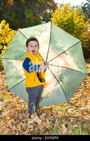 Fall. Adorable toddler boy of two years with umbrella in autumn park Stock Photo