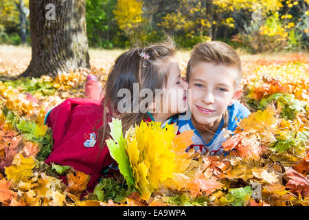 Fall. Brother and sister with leaves in autumn park Stock Photo