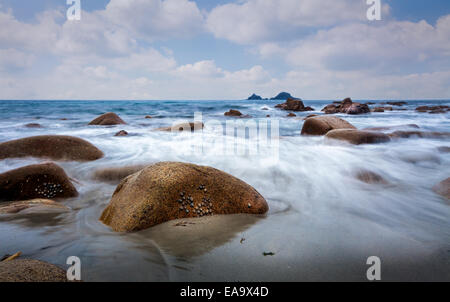 Porth Nanven Bay Cornwall long exposure seascape with prominent Rock and island on the horizon Stock Photo