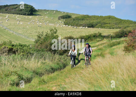 A young adult couple cycling along the South Downs Way at Butts Brow, Willingdon, near Eastbourne, East Sussex. UK Stock Photo