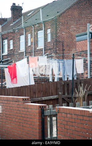 Washing or Laundry hanging on clotheslines in a residential backyard with brick terraced houses in the background Stock Photo