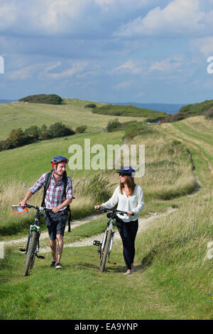 A young adult couple cycling along the South Downs Way at Butts Brow, Willingdon, near Eastbourne, East Sussex. UK Stock Photo