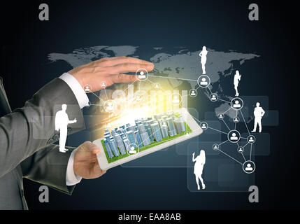 Man hands using tablet pc. Business city on touch screen. Network with business silhouettes near computer Stock Photo