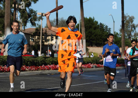 Runner dressed as Fred Flintstone competes in a 5k road race (Dino Dash) in Tustin California Stock Photo