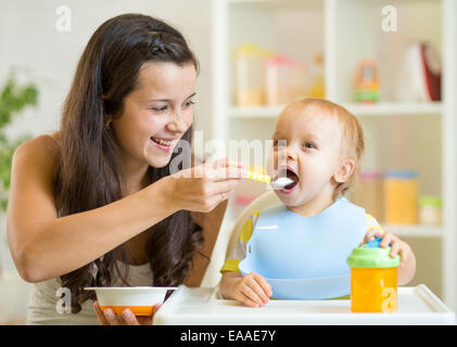 Mum spoon feeding child son Stock Photo
