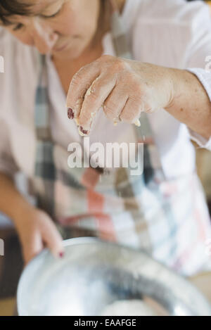 A woman measuring and sifting white flour, making a crumble topping. Home baking. Stock Photo