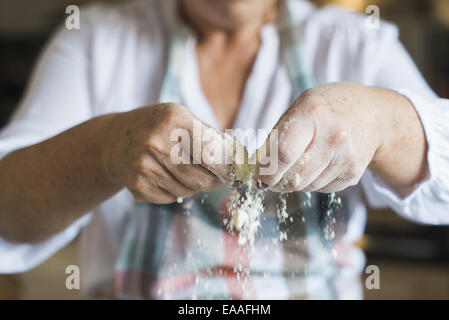 A woman crumbling and sifting white flour and butter, making a crumble topping. Home baking. Stock Photo
