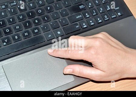 A hand of a woman working on an old laptop Stock Photo