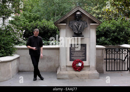 Man having a cigarette and using his mobile phone near a war memorial in The City, London Stock Photo