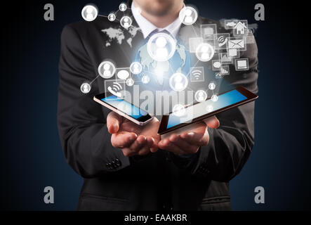 Business concept with businessman holding mobile devices. Virtual icons around Stock Photo