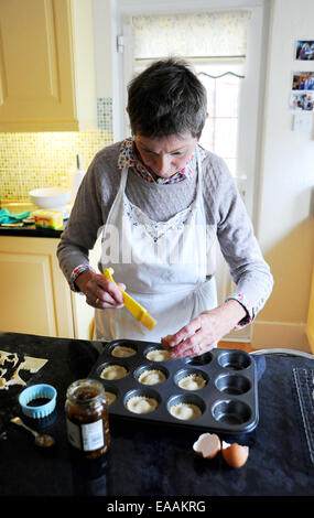 Elderly woman pensioner baking mince pies at home in her kitchen for Christmas Stock Photo