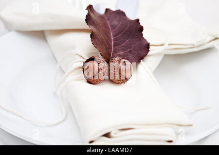 Rustic table decorated with leaves and acorns, ready for a Thanksgiving meal. Stock Photo