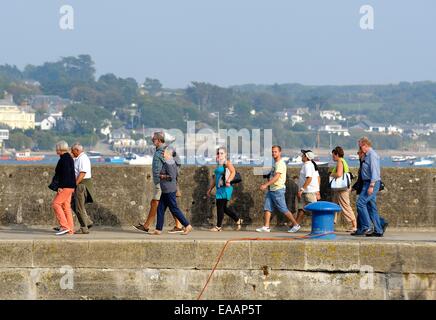 People walking along the harbour wall after disembarking from a boat trip. Padstow Cornwall England uk Stock Photo