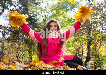 girl sitting with hand up in autumn park Stock Photo