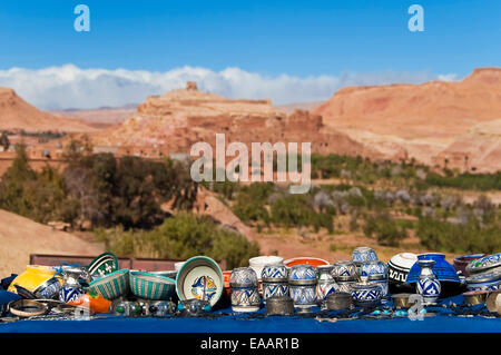 Horizontal close up of traditional Moroccan handicrafts on the roadside with Ait Benhaddou kasbah in the background.