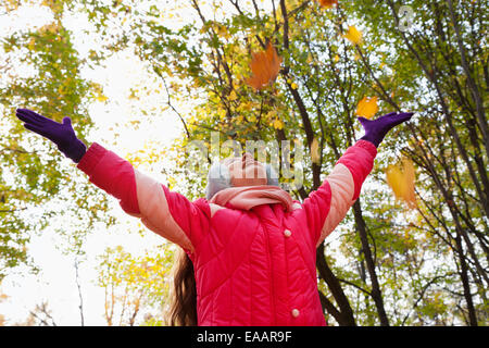 girl great pleasure from falling maple leaves in autumn park Stock Photo