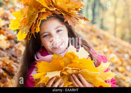 girl in a wreath of maple leaves with autumn bouquet Stock Photo