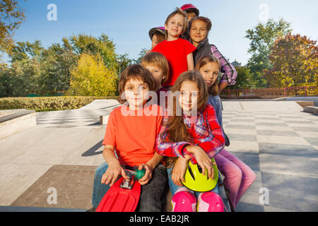 View of happy friends sitting with skateboards Stock Photo